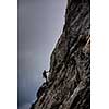 Pretty, female climber on a via ferrata - climbing on a rock in Swiss Alps