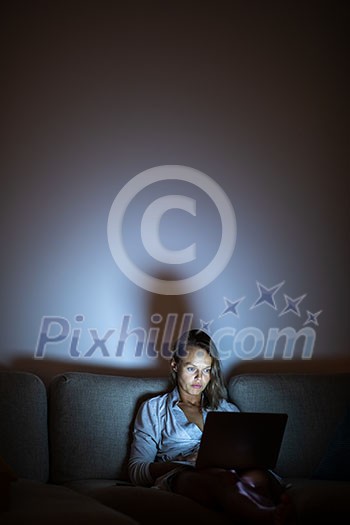 Pretty, young woman working on her laptop computer late night at her cosy home - putting in the necessary hours her job/business requires Pretty, young woman working on her laptop computer late night at her cosy home - putting in the necessary hours her job/business requires