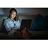 Pretty, young woman working on her laptop computer late night at her cosy home - putting in the necessary hours her job/business requires