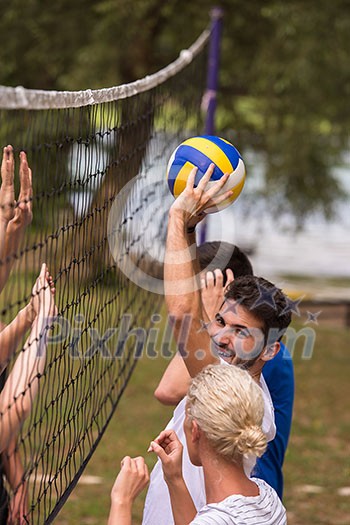 group of young friends playing Beach volleyball in a beautiful nature on the bank of the river