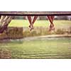 group of  people sitting at wooden bridge over the river with a focus on hanging legs