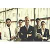 portrait of senior businessman as leader  at modern bright office interior, young  people group in background as team