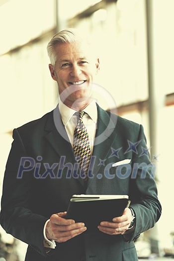 handsome senior business man with grey hair working on tablet computer at modern bright office interior handsome senior business man with grey hair working on tablet computer at modern bright office interior