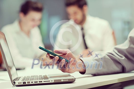 close up of businessman hands using smart phone and laptop computer, people group in office meeting room blurred in backgronud close up of businessman hands using smart phone and laptop computer, people group in office meeting room blurred in backgronud