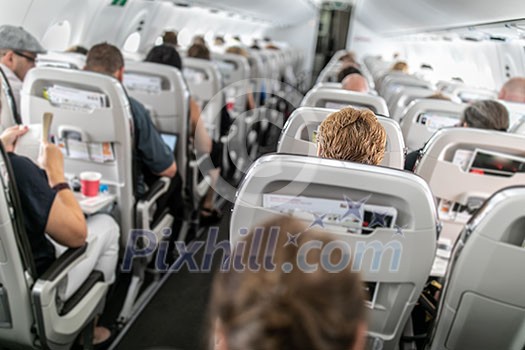 Interior of commercial airplane with passengers in their seats during flight. Interior of commercial airplane with passengers in their seats during flight.