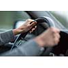 Driver's hands driving a car on a highway (color toned image; shallow DOF)