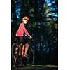 Pretty, young woman biking on a mountain bike enjoying healthy active lifestyle outdoors in summer (shallow DOF)
