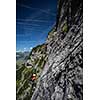 Pretty, female climber on a via ferrata - climbing on a rock in Swiss Alps