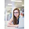 Pretty, female college student in a library, looking for a book (shallow DOF; color toned image)