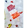 Creamy fruit colored ice cream lolly with different berries and slices of watermelon on ice cubes. Summer dietary cold dessert. Flat lay