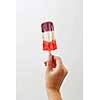 A woman's hand holds a colored berry ice cream lolly on a white background with copy space. Healthy food. Business concept concept