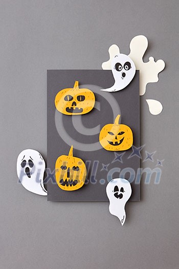 Gray frame of flying ghosts, spirits and yellow scary pumpkins, handcraft from paper on a gray background with copy space. Halloween concept. Flat lay. Gray frame of flying ghosts, spirits and yellow scary pumpkins, handcraft from paper on a gray background with copy space. Halloween concept. Flat lay.