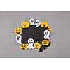 Square creative frame of black paper with handcraft laughing flying ghosts, spirits, scary pumpkins, black bats on a gray background, place for text.