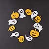 Round creative frame of colorful paper with handmade laughing flying ghosts, spirits, scary pumpkins on a black background, place for text. Halloween concept. Flat lay.