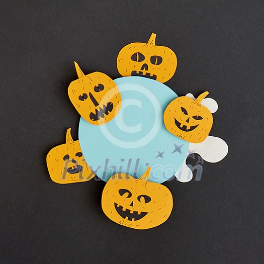Decorative application handcraft from paper with terrible yellow pumpkins smiling on a blue round frame on a black background, place for text. Halloween concept. Flat lay. Decorative application handcraft from paper with terrible yellow pumpkins smiling on a blue round frame on a black background, place for text. Halloween concept. Flat lay.