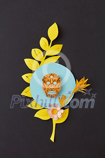 Greeting Calaca handcraft card with paper leaf branch, flower and creative skull on a blue frame on a black paper background, place under text. Skeleton Festival, the feast of death. Flat lay. Greeting Calaca handcraft card with paper leaf branch, flower and creative skull on a blue frame on a black paper background, place under text. Skeleton Festival, the feast of death. Flat lay.