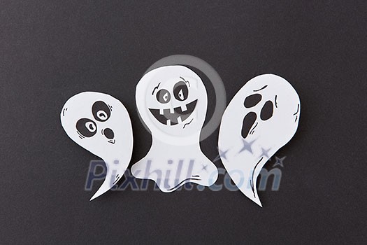 Decorative application from flying singing ghosts and spirit, smiling on a black paper background, place under text. Halloween concept. Top view. Decorative application from flying singing ghosts and spirit, smiling on a black paper background, place under text. Halloween concept. Top view.