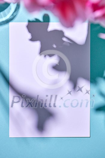 A layout for a postcard with a white sheet of paper for your text with shadows of colors on a blue background, top view A layout for a postcard with a white sheet of paper for your text with shadows of colors on a blue background, top view