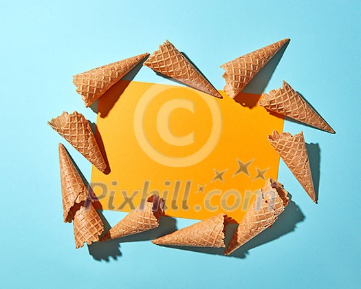 Sweet waffle cones for dessert on a duotone yellow blue paper background with copy space. Spring or summer food concept. Top view. Sweet waffle cones for dessert on a duotone yellow blue paper background with copy space. Spring or summer food concept. Top view.