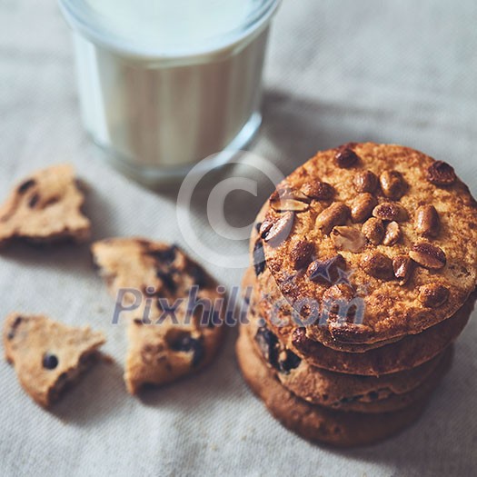 Traditional Christmas treat for Santa - homemade oatmeal cookies with peanut and glass of milk on a textile background.