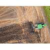 Plowing the ground after harvesting on the field in the autumn time. Aerial view from the drone of the field after harvest
