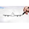 Person drawing airplane model on sky background