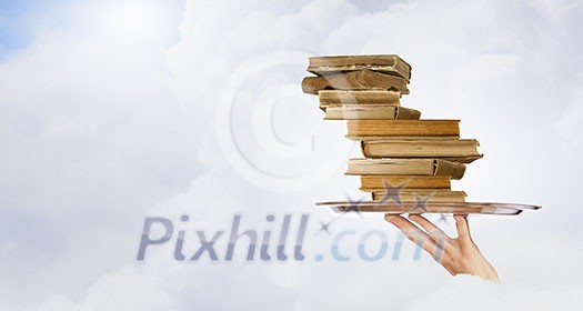 Hand holding tray with pile of old books Hand holding tray with pile of old books