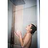 Woman taking a long hot shower washing her hair in a modern design bathroom