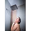 Woman taking a long hot shower washing her hair in a modern design bathroom