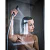 Woman taking a long hot shower washing her hair in a modern design bathroom