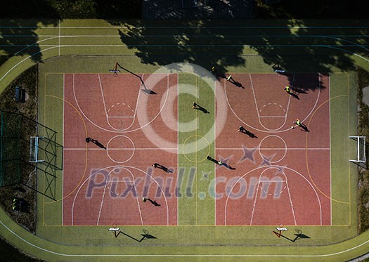 Aerial view of a soccer  pitch with people playing soccer on it - in warm morning sun, casting long shadows