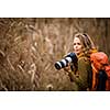 Pretty, female photographer taking pictures outdoor on a lovely autumn day - shallow DOF, color toned image