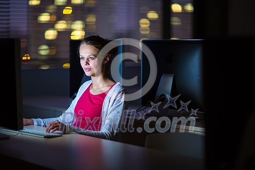 Pretty, young female college student using a desktop computer/pc in a college library - burning the midnight oil, working hard toward her goals instead of getting enough sleep (shallow DOF; color toned image) Pretty, young female college student using a desktop computer/pc in a college library - burning the midnight oil, working hard toward her goals instead of getting enough sleep (shallow DOF; color toned image)