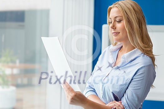 Businessowman standing next to window with papers Businessowman standing next to window with papers