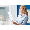 Businessowman standing next to window with papers