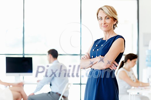 Young businesswoman standing in office with her collegue on the background Young businesswoman standing in office with her collegue on the background