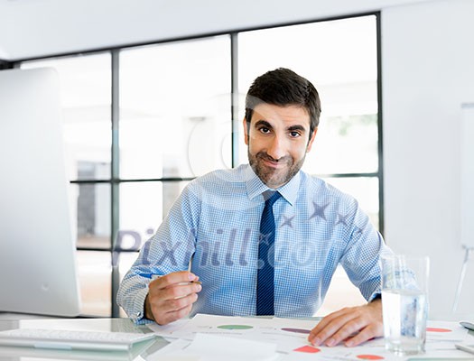 Young businessman in office sitting and smiling Young businessman in office sitting and smiling