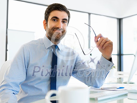 Young businessman in office sitting and smiling Young businessman in office sitting and smiling