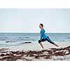 Sporty young woman stretching on the sea coast