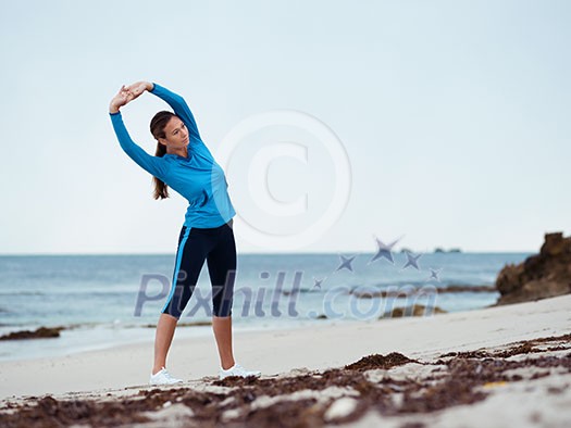 Sporty young woman stretching on the sea coast Sporty young woman stretching on the sea coast