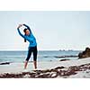 Sporty young woman stretching on the sea coast