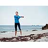 Sporty young woman stretching on the sea coast