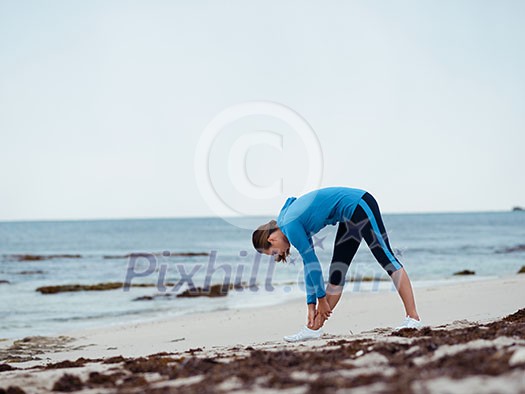 Sporty young woman stretching on the sea coast Sporty young woman stretching on the sea coast