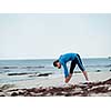 Sporty young woman stretching on the sea coast
