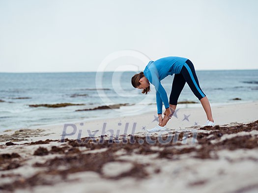 Sporty young woman stretching on the sea coast Sporty young woman stretching on the sea coast