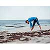 Sporty young woman stretching on the sea coast