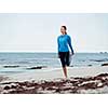 Sporty young woman stretching on the sea coast