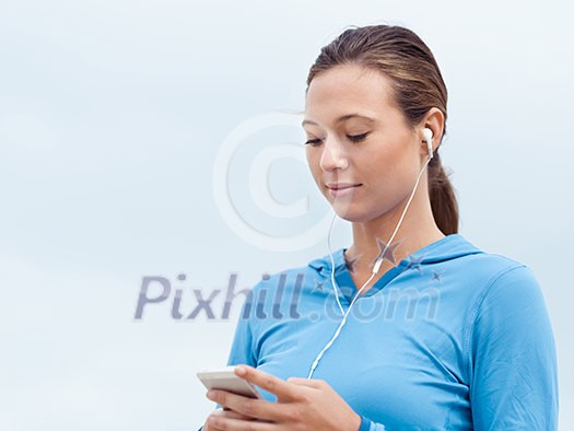 Sporty young woman with earphones on the sea coast Sporty young woman with earphones on the sea coast