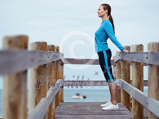 Sporty young woman stretching next to the sea coast Sporty young woman stretching next to the sea coast