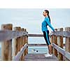 Sporty young woman stretching next to the sea coast